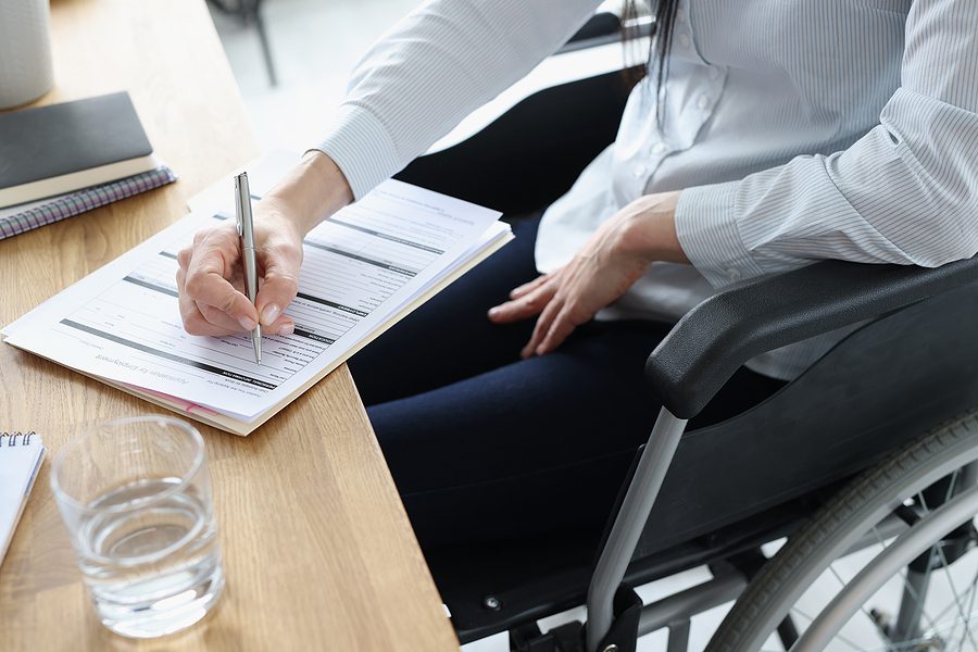 Woman sitting in wheelchair filling out forms.