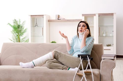 Injured woman sitting on her couch, talking on the phone.